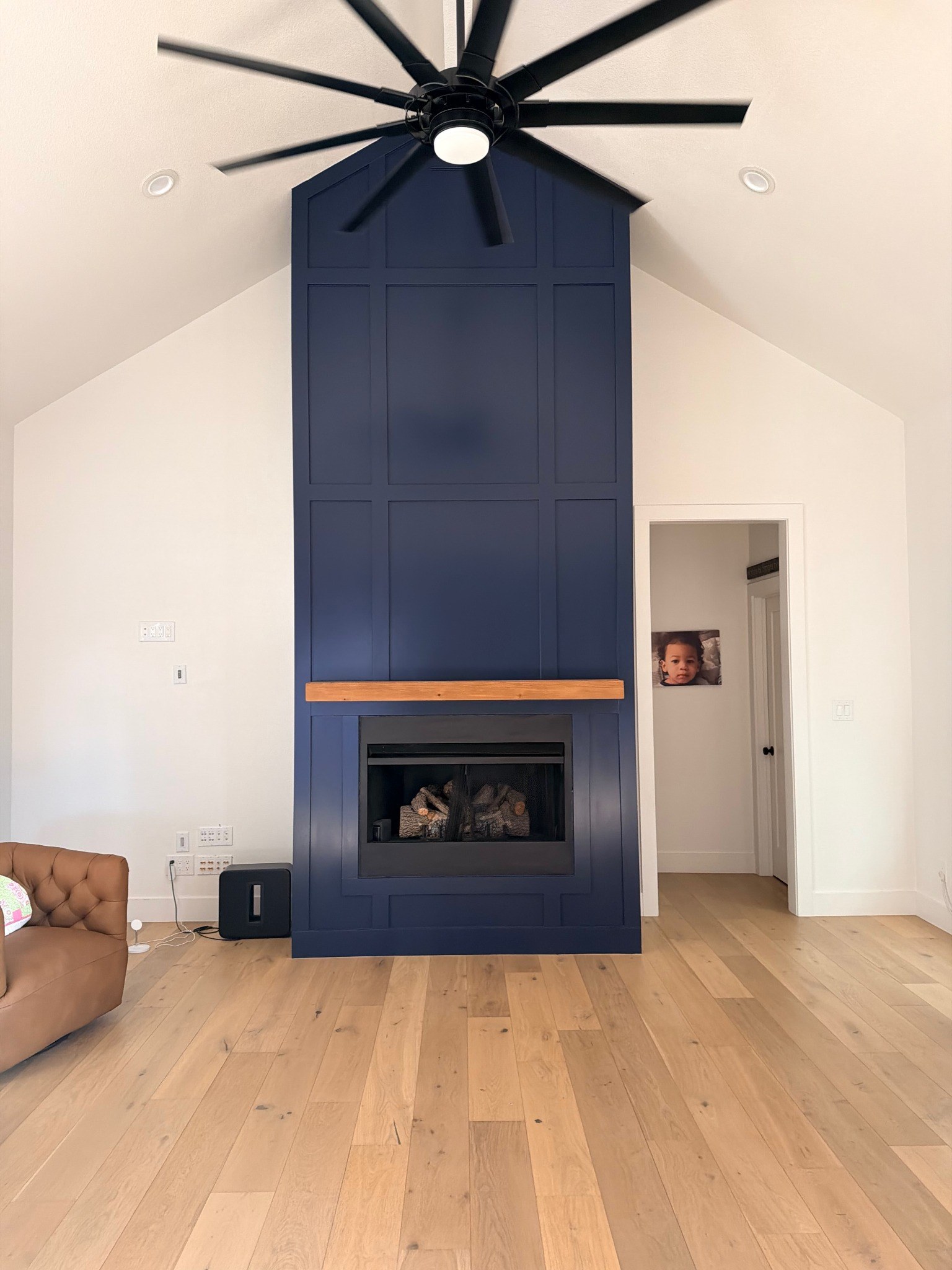 Finished navy paneled fireplace wall with wood mantel